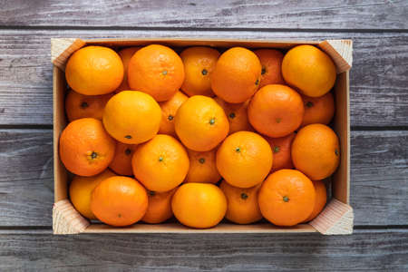 a crate with ripe orange tangerines on a wooden table top viewの写真素材