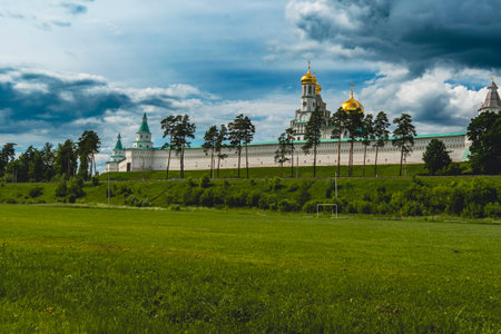 The golden domes of New Jerusalem Monastery rise above its white walls, set against a blue sky with trees in the foreground.の写真素材