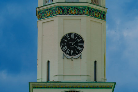 A detailed view of a clock tower featuring ornate decorations, set against a backdrop of a clear...