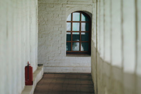 A serene view through a window in a white brick corridor, highlighting the architectural details and...