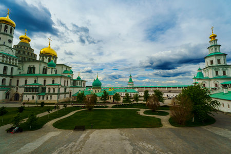 A panoramic view of a monastery featuring golden domes and a cloudy sky, capturing the serene...