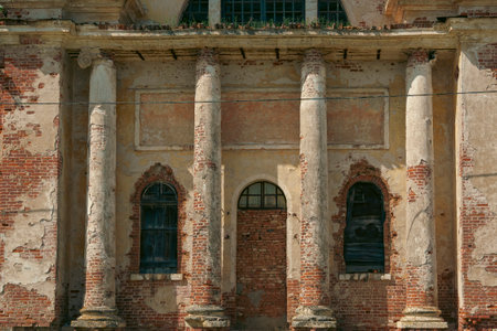 Facade of an abandoned church featuring weathered columns and deteriorating walls, showing signs of age and neglect.の写真素材