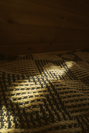 A close-up of sunlight filtering through a window and casting light on a textured woven fabric with a geometric pattern.の写真素材