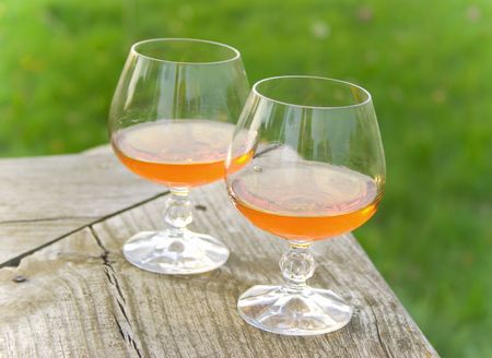 Two glasses with cognac stand on a wooden bench の写真素材