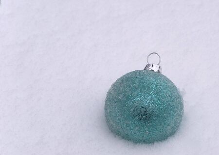 fur-tree sphere hangs on tree branch against snowの写真素材