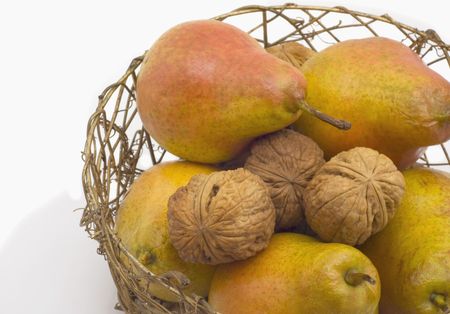 Walnuts and ripe pear lie in wattled basket whichの写真素材