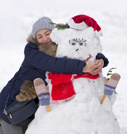 girl hugging a snowmanの写真素材