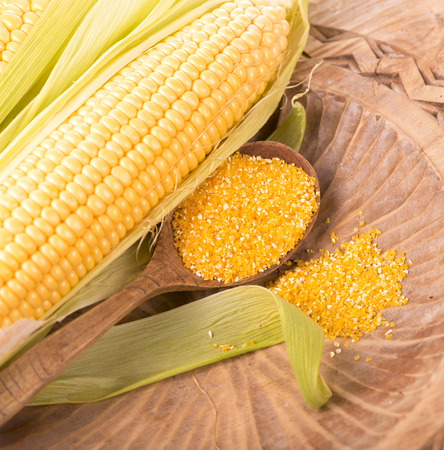 Flour corn in a spoon on the dark wooden boards