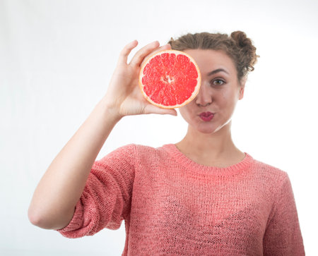 young girl holding fresh grapefruits on a white backgroundの写真素材