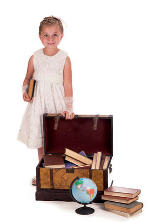 girl and a chest with books. little girl looking inside a trunk with surprise on white backgroundの写真素材
