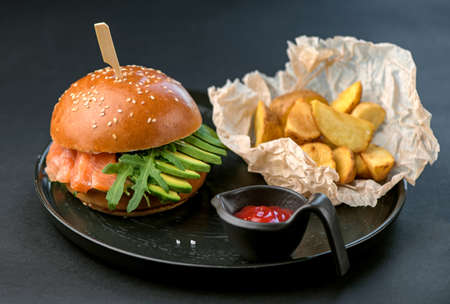 burger and fries on black plate on black backgroundの写真素材