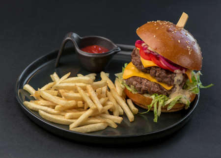 burger and fries on black plate on black background