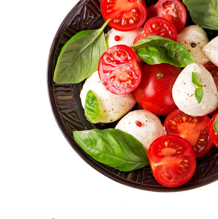 Round camembert cheese with cherry tomatoes and basil on plate.