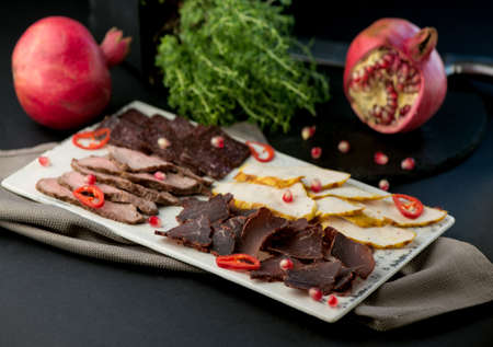 cold cuts - jamon, ham, salami on a wooden board on a black backgroundの写真素材