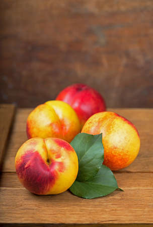 fresh nectarines with leaves on wooden backgroundの写真素材