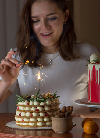Young blonde girl in her kitchen holding a Christmas cake enjoying the smell