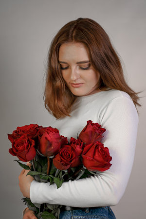 Portrait of attractive young woman holding bouquet of roses isolated on white background