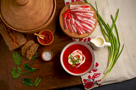 Traditional Ukrainian borsht, red vegetable soup or borscht with smetana on wooden background. Slavic dish with cabbage, beets, tomatoes Traditional Ukrainian towel along with garlic, bread and salt. Top view of a wooden tray on a black background on which lies Ukrainian food with spicesの写真素材