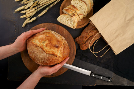 Whole grain bread put on kitchen wood plate with knife for cut. Fresh bread on table close-up. Fresh...
