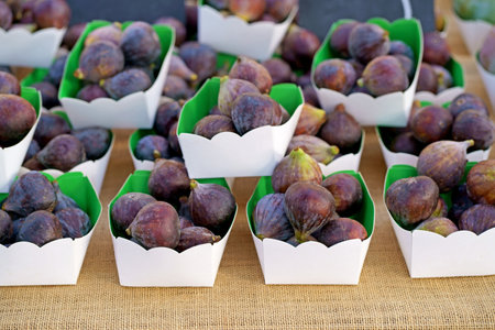 Fresh figs in a paper box. Fresh organic figs being sold on the table at a farmers marketの写真素材