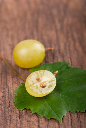 Juicy green grapes - macro shot of whole and cut berries on wooden backgroundの写真素材
