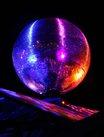 The rotating mirror sphere reflecting multi-coloured rays of light.の写真素材