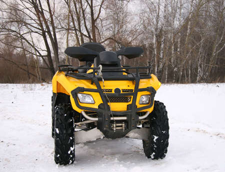The yellow cross-country vehicle in the winter on a snow floor.