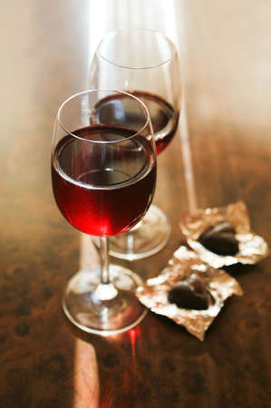 Two glasses of red wine and two chocolates