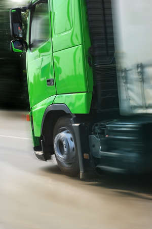 big truck with a green cabin going on highway