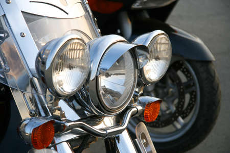 Three chromeplated headlights on a forward suspension bracket of a motorcycle の写真素材