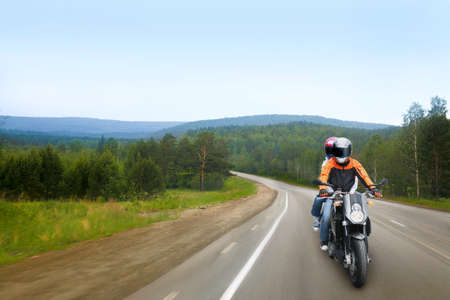 motorcyclist and passenger go on country roadの写真素材