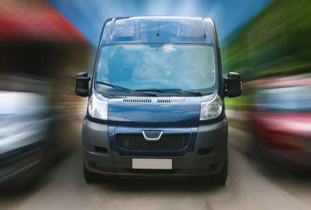 dark blue minibus goes on city street