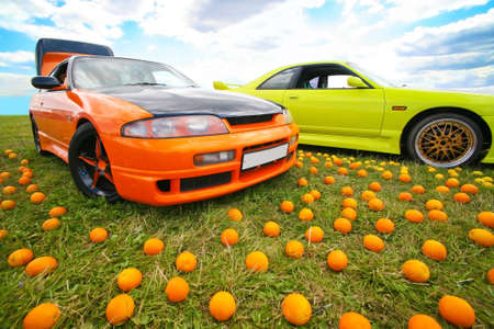 Two bright colour cars and fruit on grassの写真素材