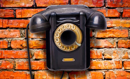 Old black rotational phone on wallの写真素材