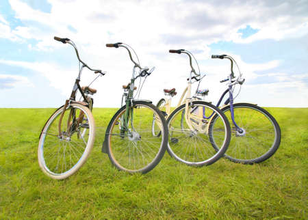 four bicycles on meadow against the skyの写真素材