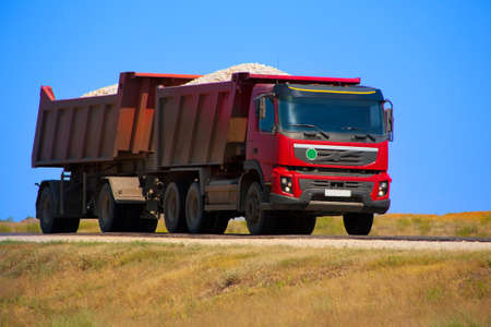 red dump truck with the trailer loaded with rubbleの写真素材