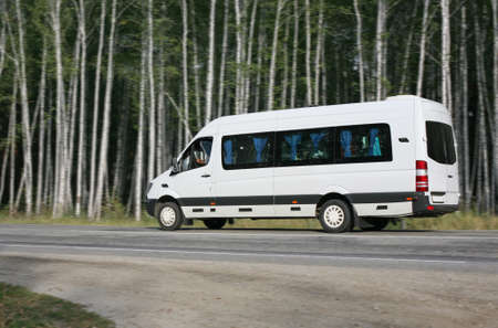  white minibus goes on the forest roadの写真素材