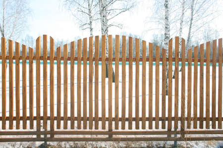 winter field protected with wooden fenceの写真素材