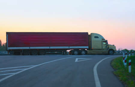 big trailer goes on  motorway against sunsetの写真素材
