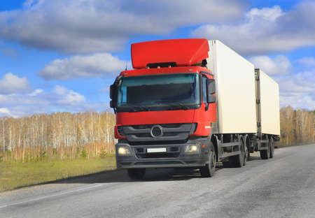 big trailer with red cabin goes on roadの写真素材