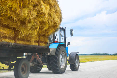 tractor transports haystack on the trailer on the roadの写真素材