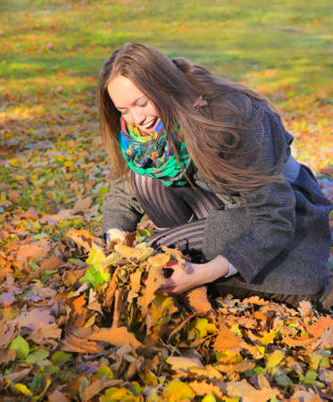 cheerful girl plays with leaves in autumn parkの写真素材
