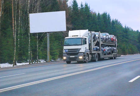 truck transports car against winter forest