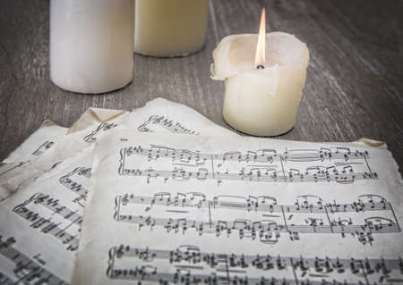 music notes on old paper and candles on tableの写真素材