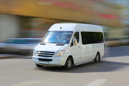white minibus goes on the city streetの写真素材
