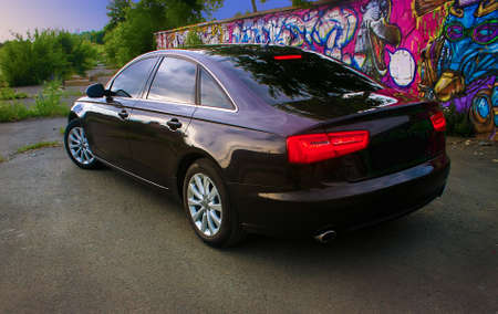 prestigious dark car near wall with graffitiの写真素材