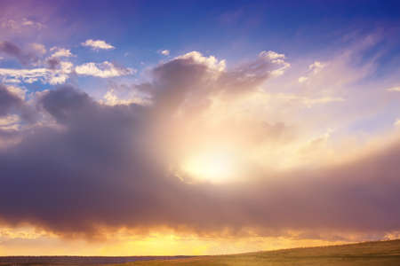 beautiful sunset in the cloudy sky over fieldの写真素材