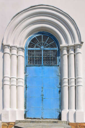 blue metal door of the white plastered churchの写真素材