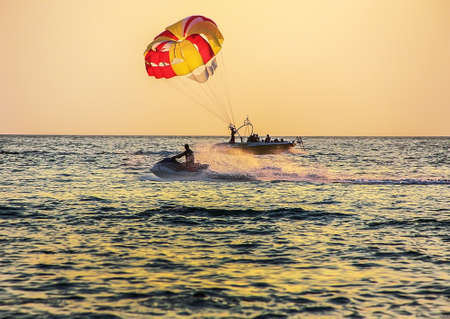 boat with parachute and water bike at sea on sunsetの写真素材