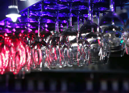 glasses hanging on an arm over a bar counterの写真素材